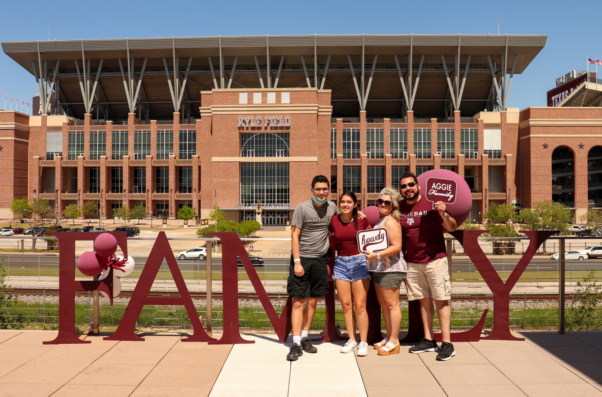family posing for photo in front of Kyle Field on a sunny day